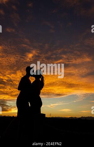 Silhouette d'un jeune couple embrassant sur la plage de nelson au coucher du soleil sur la plage de Tahunanui à Nelson, Nouvelle-Zélande. Banque D'Images