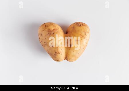 Pommes de terre en forme de cœur sur fond blanc. La nourriture est horrible, c'est le concept de la Saint Valentin. Banque D'Images