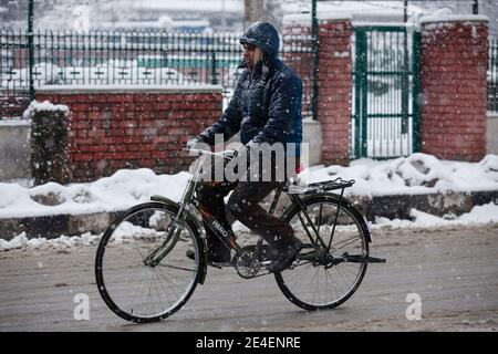 Srinagar, Cachemire sous contrôle indien. 23 janvier 2021. Un homme fait un vélo au milieu des chutes de neige dans la ville de Srinagar, la capitale estivale du Cachemire sous contrôle indien, le 23 janvier 2021. Samedi, une chute de neige a frappé le Cachemire contrôlé par l'Inde. Crédit : Javed Dar/Xinhua/Alay Live News Banque D'Images