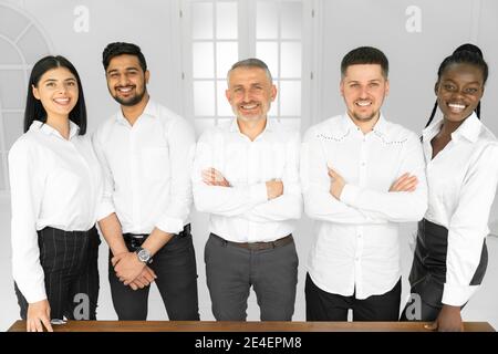 Portrait de debout dans la rangée souriant équipe diverse posant, le tout dans des chemises blanches. Joyeux jeune personnel multiethnique d'entreprise, séance photo des employés de banque, HR ag Banque D'Images