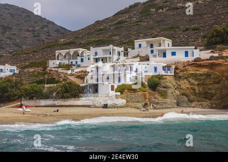 Agkali Beach, Folegandros Island, Grèce- 24 septembre 2020 : villas à flanc de coteau blanc à côté d'une plage de sable. Les touristes nageant dans la mer et se détendant Banque D'Images