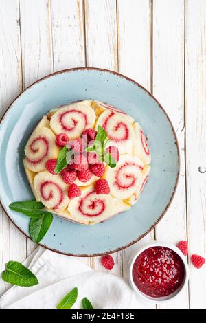 Gâteau royal de Charlotte rafraîchissant rempli de confiture de framboises et décoré avec baies fraîches sur table rustique en bois Banque D'Images