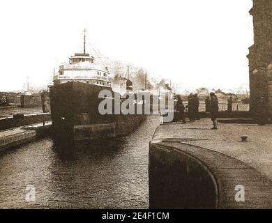 Une photographie imprimée des années 1940 de navires passant par le canal Saulte Sainte Marie (alias canal St. Marys Falls, canal Soo, Sault Ste Marie canal ou écluses de Sault) qui permettent aux navires de se déplacer entre le lac supérieur et les Grands Lacs inférieurs. Les serrures se ferment pendant l'hiver de janvier à mars, mais la période est utilisée pour inspecter et entretenir les serrures. Les premières écluses ont été ouvertes en 1855 et ont été gardées par le Commandement de la défense centrale de l'armée américaine pendant la Seconde Guerre mondiale. Banque D'Images