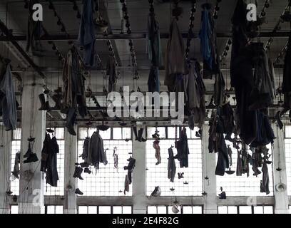 Vestiaire d'une ancienne usine industrielle : vêtements de travail suspendus au plafond Banque D'Images