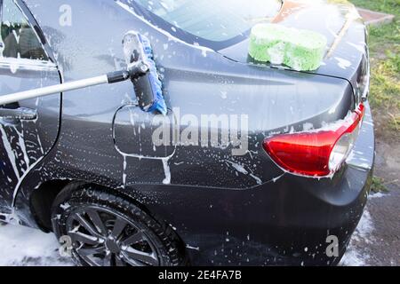 Concept de lavage de voiture extérieur, lavage d'une voiture avec une brosse en mousse Banque D'Images