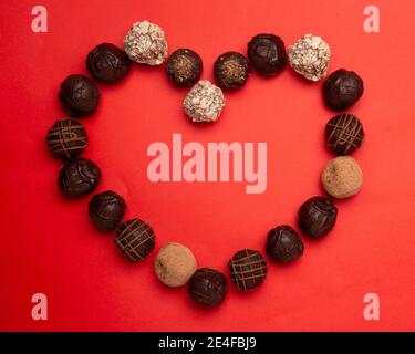 image concept d'amour de la forme du coeur fait de truffes au chocolat sur fond de texture de papier rouge Banque D'Images