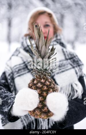 Une fille en moufles tient l'ananas en hiver Banque D'Images