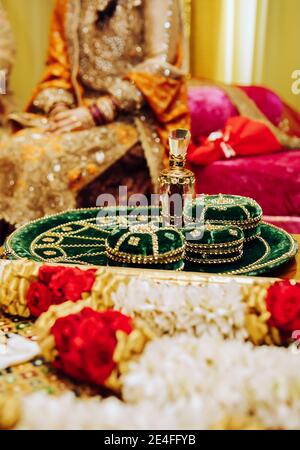 Arrière-plan de la fête de mariage de henné indien pakistanais avec des fleurs traditionnelles, mehndi vert assiette en velours et mariée dans la robe jaune brodée avec des pierres précieuses Banque D'Images