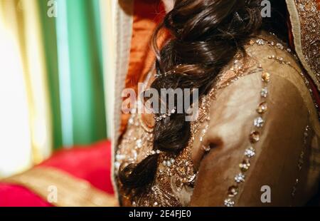 Gros plan sur une mariée pakistanaise indienne tresse à cheveux foncés sous foulard avec la décoration de bijoux pendant la fête de mariage henné mehndi sangeet Banque D'Images