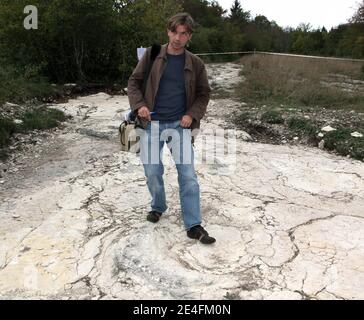 Journaliste se tenant en face de la découverte récente d'un sauropode bien conservé empreintes de dinosaures, entre 1.5 et deux mètres de diamètre dans les environs de Plagne, Jura, est de la France, le 6 octobre 2009. La découverte, qui a été faite en avril et date d'il y a 150 millions d'années, a été authentifiée par les scientifiques comme une découverte unique. Il s'agit peut-être des plus grandes traces de dinosaures jamais découvertes dans le monde, selon le Conseil National de recherche Français (CNRS).photo de Vincent Dargent/ABACAPRESS.COM Banque D'Images