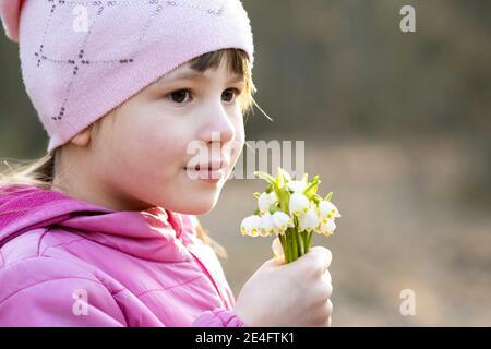 Portrait d'une jeune fille heureuse tenant un bouquet de fleurs de neige printanière plein air. Banque D'Images