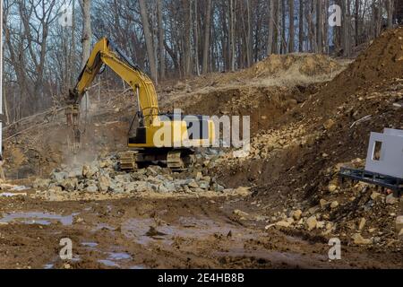 Tracteur pour l'écrasement de grosses pierres sur un pendant les travaux de terrassement au chantier de construction en montagne Banque D'Images