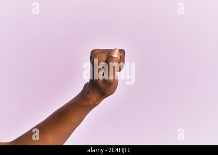 Bras et main de la femme d'âge moyen noire sur fond rose isolé tenant un espace vide avec le pouce, les affaires et la publicité Banque D'Images