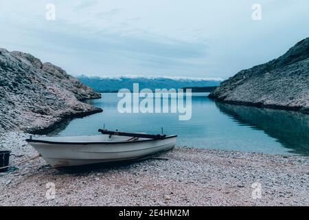 Bateau sur la plage et sommets enneigés des montagnes Velebit en arrière-plan, Nin, Croatie. Banque D'Images