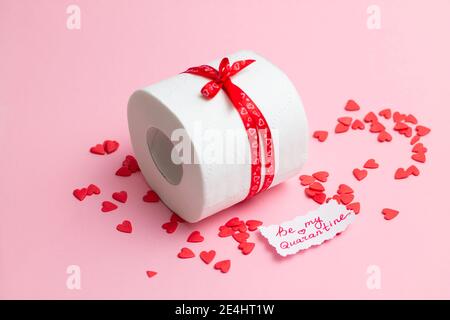 Rouleau de papier toilette en cadeau de la Saint-Valentin avec note « soyez ma quarantaine », à côté de coeurs rouges sur fond rose Banque D'Images