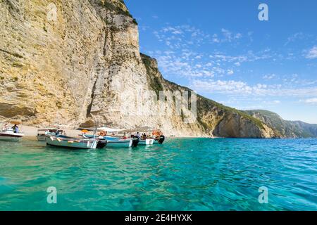 Ligne de bateaux jusqu'au rivage dans les eaux claires de la plage de Paradise Beach ou Chomi Beach sur une journée ensoleillée à Corfou en Grèce. Banque D'Images