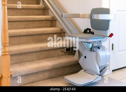 Une vie électrique et motorisée de chaise pour les personnes handicapées sur un escalier de moquette dans une maison résidentielle. Banque D'Images