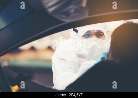 Asian Woman Drive-Thru Covid-19 Test avec le personnel médical PPE, COVID test temp lors de l'enregistrement de voitures Banque D'Images