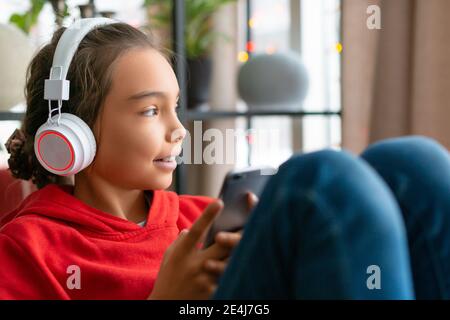 Une adolescente écoute de la musique via un casque via une application en ligne sur un téléphone portable. Concept de technologie moderne. Banque D'Images