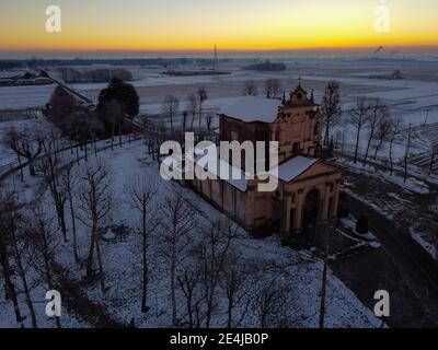Soleil levant au-dessus de la plaine enneigée et du sanctuaire de Varalino di Galliate, Novara, Piémont, Italie Banque D'Images