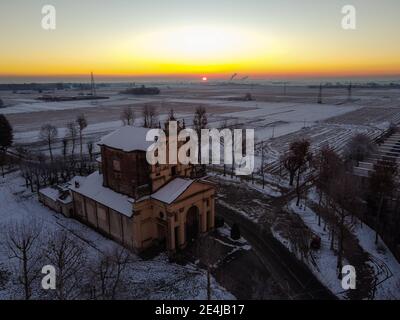 Soleil levant au-dessus de la plaine enneigée et du sanctuaire de Varalino di Galliate, Novara, Piémont, Italie Banque D'Images
