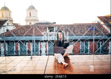 Jeune femme avec une tasse de café rêve en se tenant sur le toit de la ville Banque D'Images