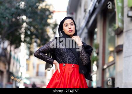 Portrait de la jeune femme portant le hijab noir posant à l'extérieur avec main sur la hanche Banque D'Images