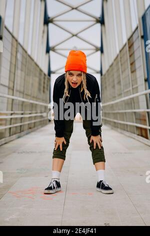 Jeune femme avec la bouche ouverte fléchissant en se tenant sur la passerelle Banque D'Images