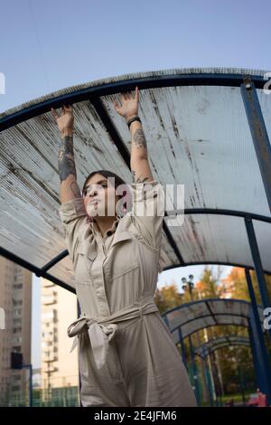 Jeune femme avec tatouage suspendu sur le toit tout en regardant loin sur un terrain de sport Banque D'Images