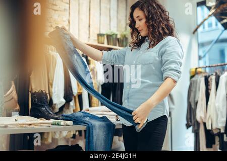 Femme regardant une qualité de jeans dans un magasin de vêtements. Un acheteur achète un Jean dans un magasin de mode. Banque D'Images