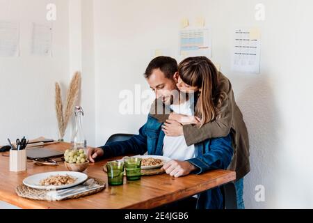 Femme d'affaires avec le bras autour de l'embrassant collègue mâle à la table dedans séjour Banque D'Images
