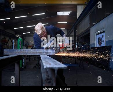 Travailleur manuel utilisant un matériau de coupe à l'aide d'une meuleuse circulaire pendant le travail en usine Banque D'Images