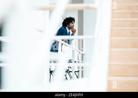 Homme d'affaires attentionné penché sur la rampe par l'escalier dans le bureau Banque D'Images