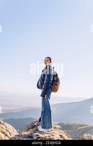 Randonneur féminin avec sac à dos debout sur le dessus de la montagne contre ciel dégagé Banque D'Images