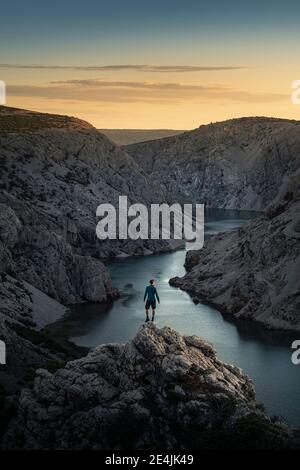 Homme debout sur des rochers et regardant la rivière dans le canyon au coucher du soleil Banque D'Images