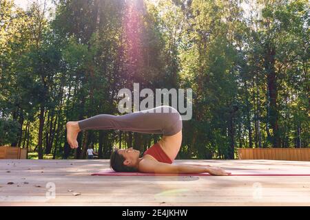 Portrait d'une jeune femme qui fait du yoga à l'extérieur. Rayons du soleil levant et de l'éblouissement Banque D'Images