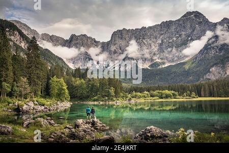 Homme et femme debout au bord du lac en paysage de montagne Banque D'Images