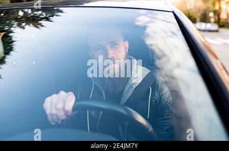 Homme barbu conduisant la voiture vu à travers le pare-brise Banque D'Images