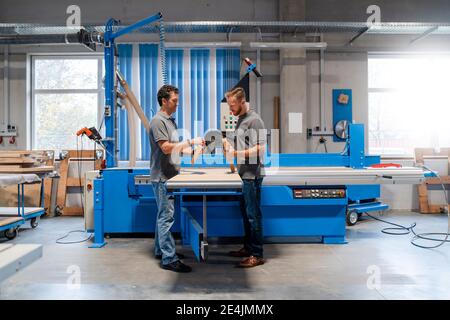 Deux menuisiers masculins parlent dans la salle de production Banque D'Images