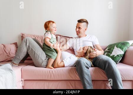 Famille heureuse avec bébé fille se détendre sur le canapé Banque D'Images