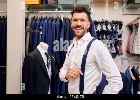 Portrait d'un homme souriant en chemise blanche et bretelles bleues boutique des tailleurs Banque D'Images