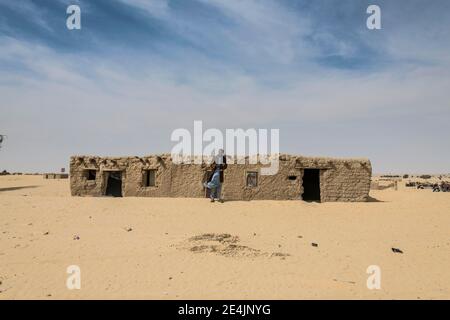 Homme en face d'une maison de boue traditionnelle, un village dans le désert, entre Faya-Largeaux et n'Djamena, Sahara, Tchad Banque D'Images