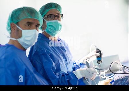 Chirurgien masculin spécialisé qui regarde l'équipement de surveillance pendant son fonctionnement en soins intensifs Banque D'Images