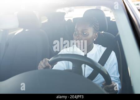 Femme vue à travers le pare-brise en conduisant la voiture Banque D'Images