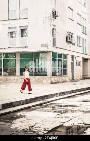 Femme passant devant le vieux bâtiment Banque D'Images