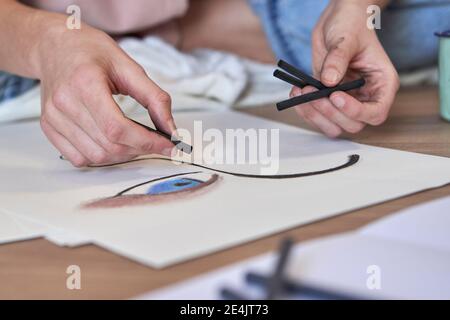 Femme artiste faisant le dessin de charbon de bois sur le papier dans le salon Banque D'Images