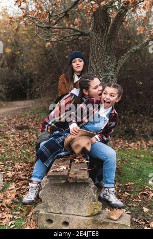 Trois sœurs souriantes sur le banc en paysage d'automne Banque D'Images