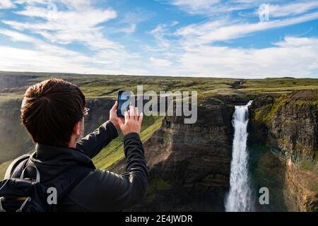 Touriste prenant photo de la cascade de Haifoss par téléphone portable pendant debout en Islande Banque D'Images