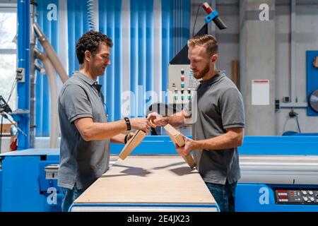 Deux menuisiers masculins parlent dans la salle de production Banque D'Images