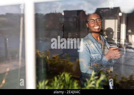 Femme souriante avec les yeux fermés à la fenêtre Banque D'Images